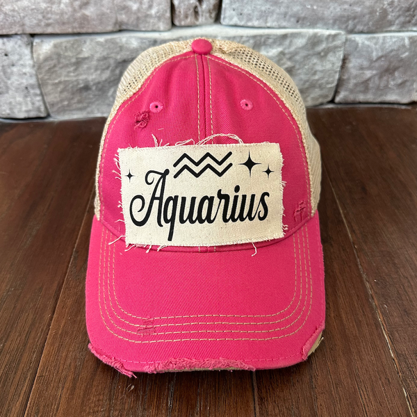 Pink cap with 'Aquarius' patch on a wooden surface