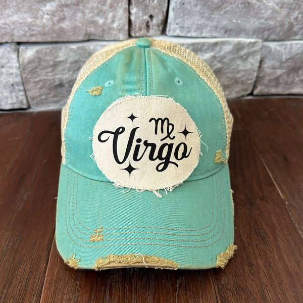 Teal cap with 'Virgo' patch on a wooden surface and stone wall background