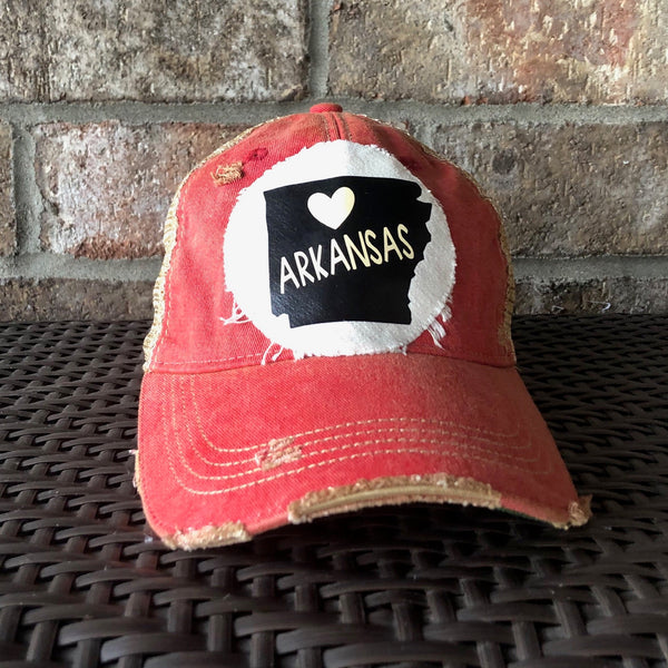 Arkansas hat by BohoGroove with black Arkansas state graphic and white heart on a distressed off-white custom patch on a red vintage distressed snapback trucker hat.