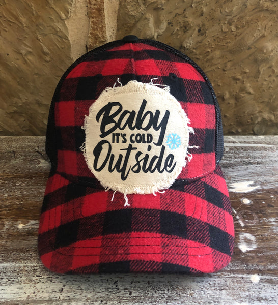 Baby It's Cold Outside hat by BohoGroove with black Baby It's Cold Outside lettering and a blue snowflake graphic on a distressed off-white patch on a red and black buffalo plaid snapback trucker hat.