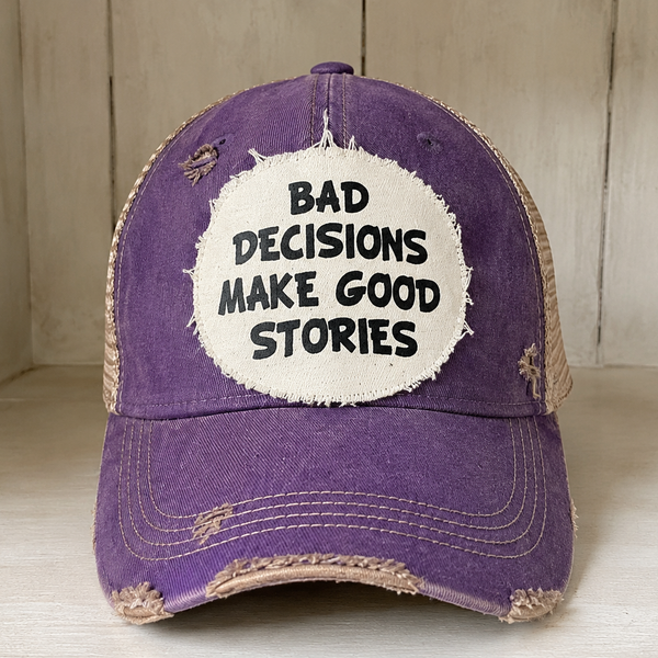 Bad Decisions Make Good Stories hat by BohoGroove with black Bad Decisions Make Good Stories lettering on a distressed off-white patch on a purple vintage distressed snapback trucker hat.