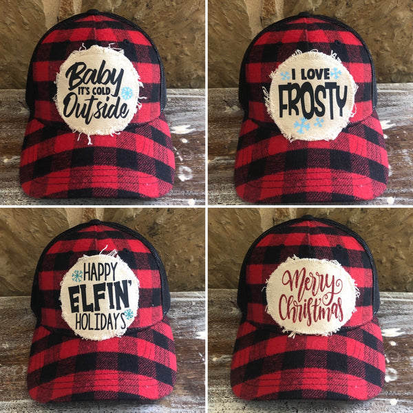 Buffalo plaid Christmas hat collection by BohoGroove featuring Baby It's Cold Outside, I Love Frosty, Happy Elfin' Holidays, and Merry Christmas designs on red and black buffalo plaid snapback trucker hats with distressed off-white patches.