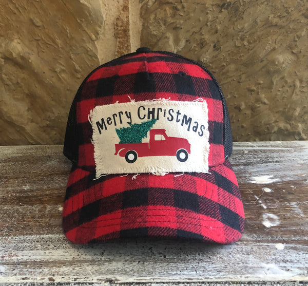 Buffalo Plaid Christmas Truck hat by BohoGroove with black Merry Christmas lettering, a red vintage pickup truck carrying a green Christmas tree, and distressed off-white patch on a red and black buffalo plaid snapback trucker hat.