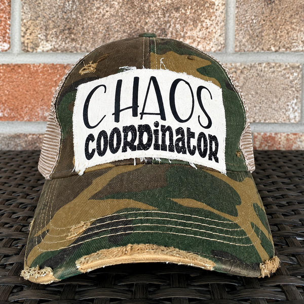 Chaos Coordinator hat by BohoGroove with black Chaos Coordinator lettering on a distressed off-white patch on a camo vintage distressed snapback trucker hat.