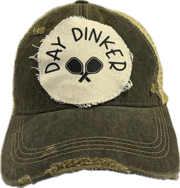 Day Dinker hat by BohoGroove featuring black Day Dinker lettering and crossed pickleball paddles graphic on a distressed off-white patch on a black vintage distressed snapback trucker hat.