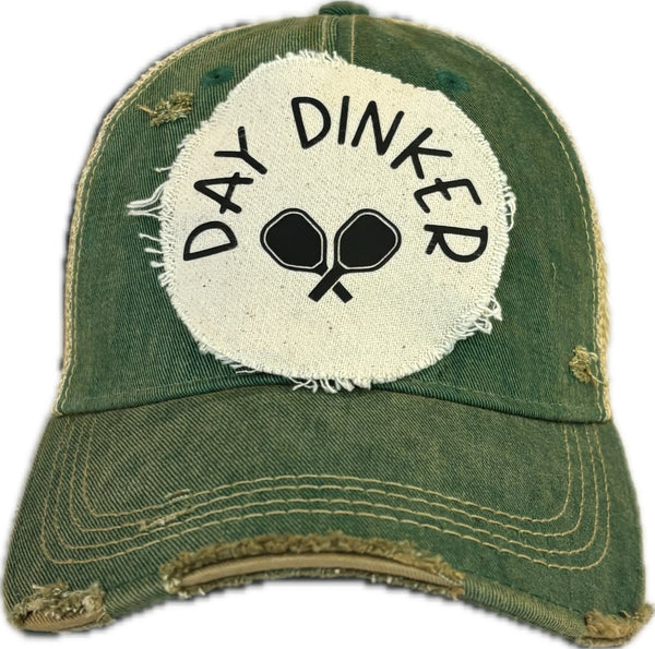 Day Dinker hat by BohoGroove featuring black Day Dinker lettering and crossed pickleball paddles graphic on a distressed off-white patch on a green vintage distressed snapback trucker hat.