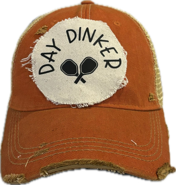 Day Dinker hat by BohoGroove featuring black Day Dinker lettering and crossed pickleball paddles graphic on a distressed off-white patch on an orange vintage distressed snapback trucker hat.