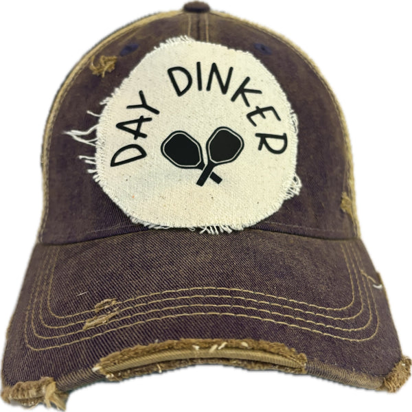 Day Dinker hat by BohoGroove featuring black Day Dinker lettering and crossed pickleball paddles graphic on a distressed off-white patch on a purple vintage distressed snapback trucker hat.