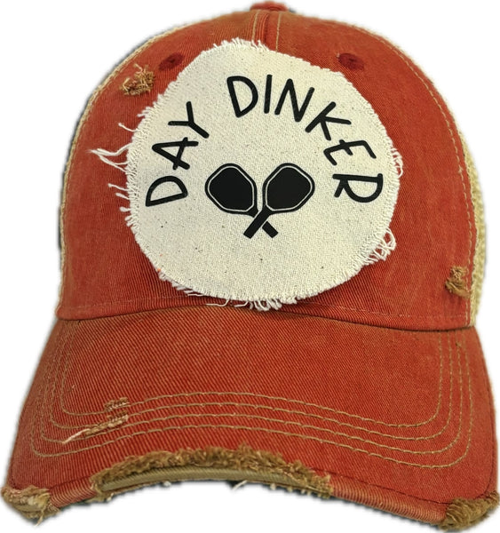 Day Dinker hat by BohoGroove featuring black Day Dinker lettering and crossed pickleball paddles graphic on a distressed off-white patch on a red vintage distressed snapback trucker hat.