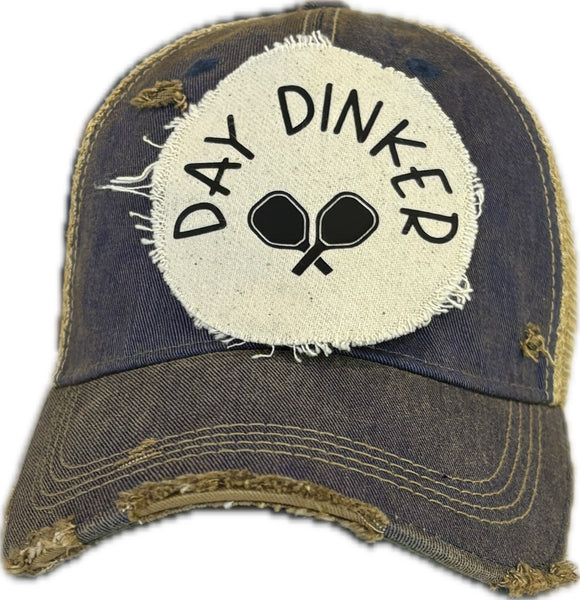 Day Dinker hat by BohoGroove featuring black Day Dinker lettering and crossed pickleball paddles graphic on a distressed off-white patch on a royal blue vintage distressed snapback trucker hat.