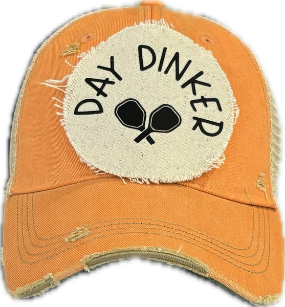 Day Dinker hat by BohoGroove featuring black Day Dinker lettering and crossed pickleball paddles graphic on a distressed off-white patch on a sherbet vintage distressed snapback trucker hat.