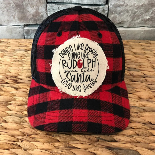Frosty Rudolph Santa Jesus hat by BohoGroove with Dance Like Frosty, Shine Like Rudolph, Give Like Santa, Love Like Jesus wording on a distressed off-white patch on a red and black buffalo plaid snapback trucker hat.