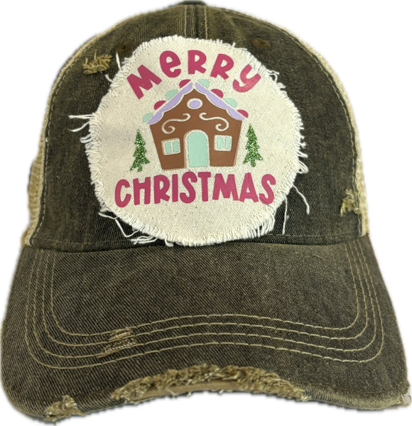 Gingerbread House hat by BohoGroove with pink Merry Christmas lettering, a gingerbread house graphic, and green trees on a distressed off-white patch on a black vintage distressed snapback.
