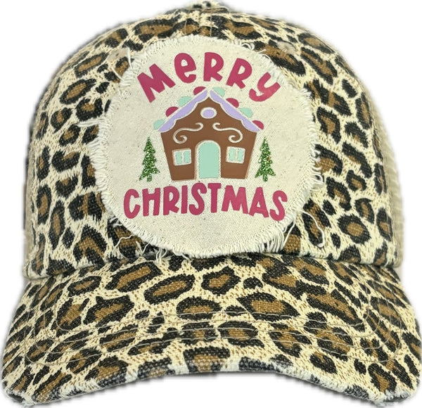 Gingerbread House hat by BohoGroove with pink Merry Christmas lettering, a gingerbread house graphic, and green trees on a distressed off-white patch on a leopard vintage distressed snapback.