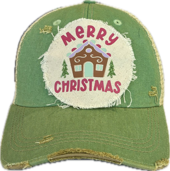 Gingerbread House hat by BohoGroove with pink Merry Christmas lettering, a gingerbread house graphic, and green trees on a distressed off-white patch on a mint vintage distressed snapback.