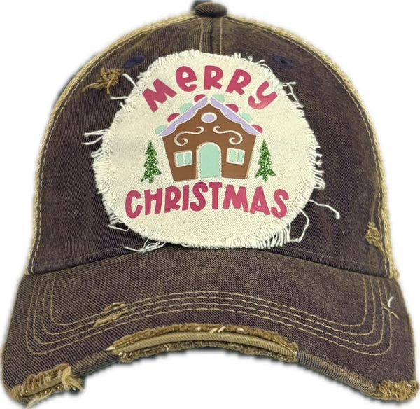 Gingerbread House hat by BohoGroove with pink Merry Christmas lettering, a gingerbread house graphic, and green trees on a distressed off-white patch on a purple vintage distressed snapback.