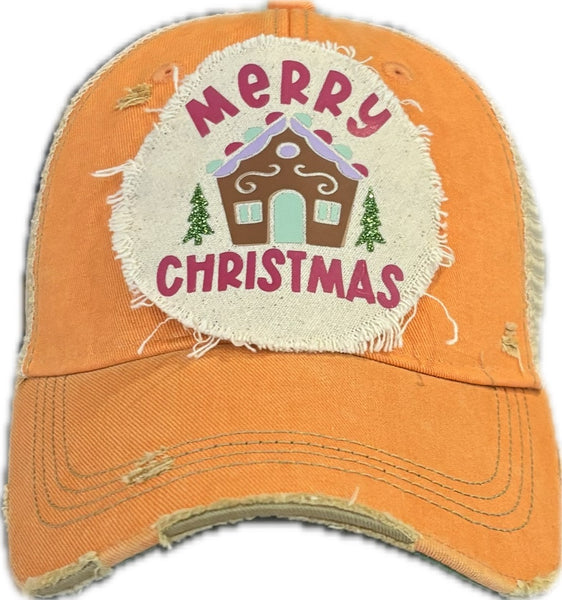 Gingerbread House hat by BohoGroove with pink Merry Christmas lettering, a gingerbread house graphic, and green trees on a distressed off-white patch on a sherbet vintage distressed snapback.