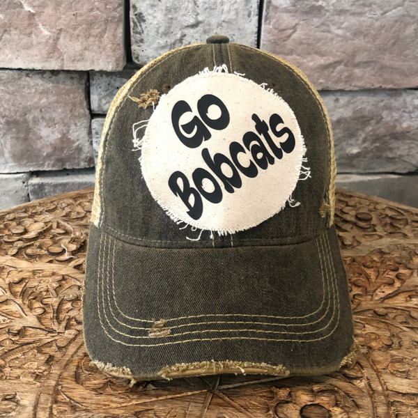 Go Bobcats hat by BohoGroove featuring black Go Bobcats lettering on a round cream frayed patch on a black vintage distressed snapback trucker hat.