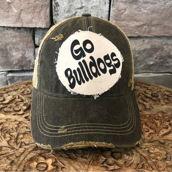 Go Bulldogs hat by BohoGroove featuring black Go Bulldogs lettering on a round cream frayed patch on a black vintage distressed snapback trucker hat.