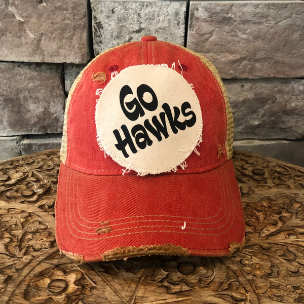 Go Hawks hat by BohoGroove featuring black Go Hawks lettering on a round cream frayed patch on a red vintage distressed snapback trucker hat.