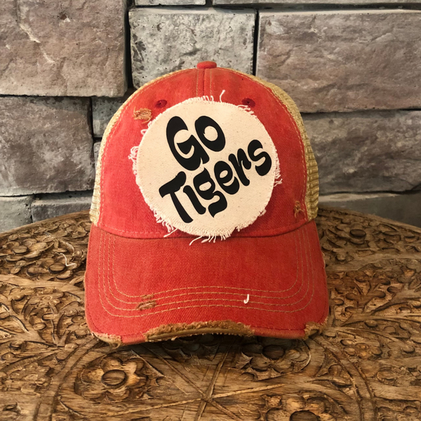 Go Tigers hat by BohoGroove featuring black Go Tigers  lettering on a round cream frayed patch on a red vintage distressed snapback trucker hat.