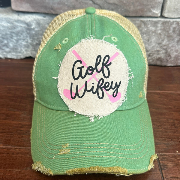 Golf Wifey hat by BohoGroove featuring black Golf Wifey lettering and pink crossed golf clubs on a mint vintage distressed snapback hat