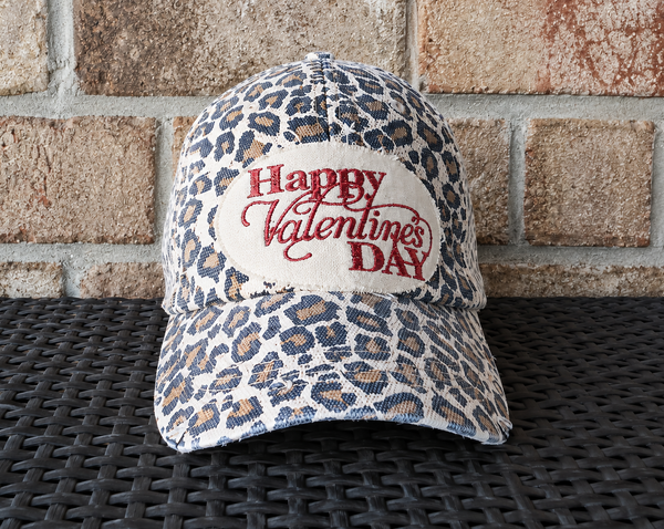 Happy Valentine’s Day hat by BohoGroove with red glitter Happy Valentine’s Day lettering on a distressed off-white patch on a leopard vintage distressed snapback trucker hat.
