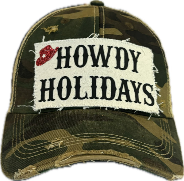 Howdy Holidays Cowboy Hat by BohoGroove with black Howdy Holidays lettering and a red glitter cowboy hat graphic on a distressed off-white custom patch on a camo vintage distressed snapback.