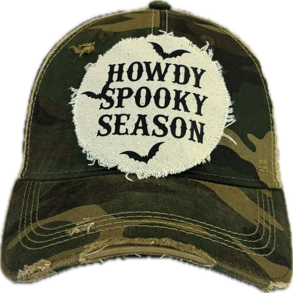 Howdy Spooky Season hat by BohoGroove with black wording and bat graphics on a distressed off-white patch on a camo vintage distressed snapback trucker hat.
