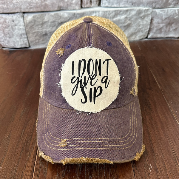 I Don't Give a Sip hat by BohoGroove featuring a funny drinking saying patch on a purple vintage distressed snapback trucker hat.