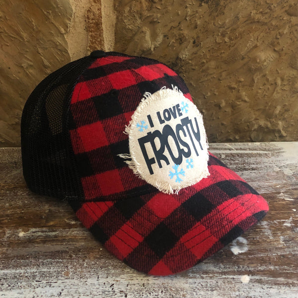 Left side view of the I Love Frosty hat by BohoGroove featuring black I Love Frosty lettering and blue snowflake accents on a distressed off-white patch on a red and black buffalo plaid snapback trucker hat with black mesh back.