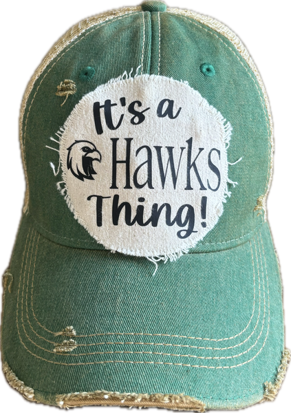 It's a Hawks Thing hat by BohoGroove featuring black lettering and a hawk graphic on a round cream frayed patch on a green vintage distressed snapback trucker hat.
