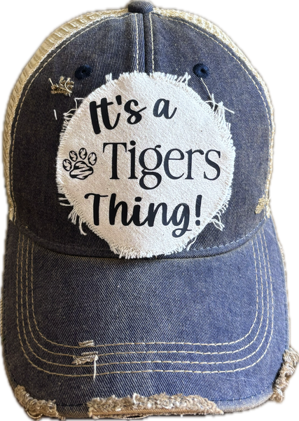 It's a Tigers Thing hat by BohoGroove featuring black lettering and a tiger paw graphic on a round cream frayed patch on a navy vintage distressed snapback trucker hat.