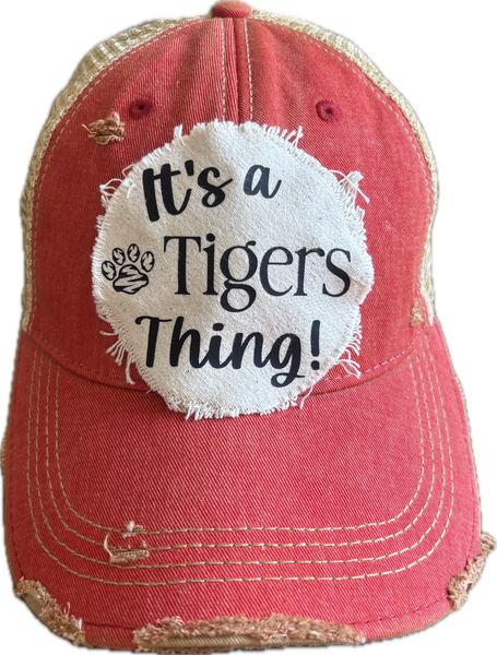 It's a Tigers Thing hat by BohoGroove featuring black lettering and a tiger graphic on a round cream frayed patch on a red vintage distressed snapback trucker hat.
