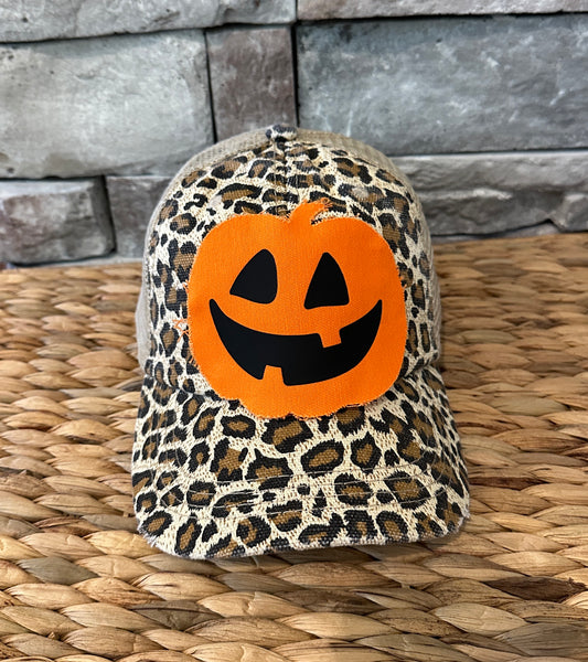 Jack-o’-Lantern hat by BohoGroove with orange pumpkin face design on a leopard vintage distressed snapback trucker hat.