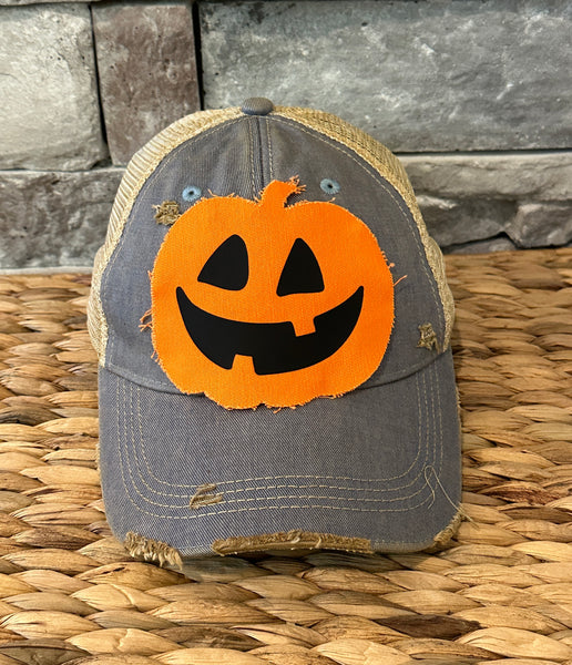 Jack-o’-Lantern hat by BohoGroove with orange pumpkin face design on a light blue vintage distressed snapback trucker hat.