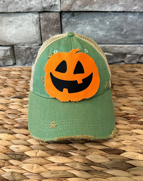Jack-o’-Lantern hat by BohoGroove with orange pumpkin face design on a mint vintage distressed snapback trucker hat.