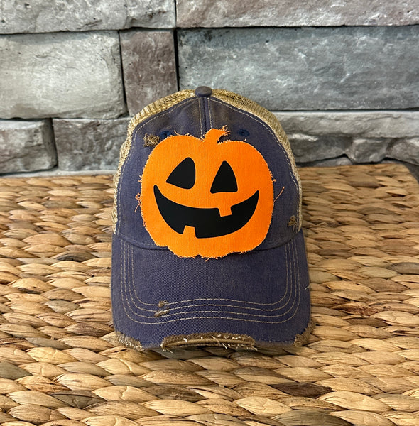 Jack-o’-Lantern hat by BohoGroove with orange pumpkin face design on a navy blue vintage distressed snapback trucker hat.