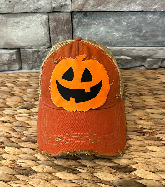 Jack-o’-Lantern hat by BohoGroove with orange pumpkin face design on an orange vintage distressed snapback trucker hat.
