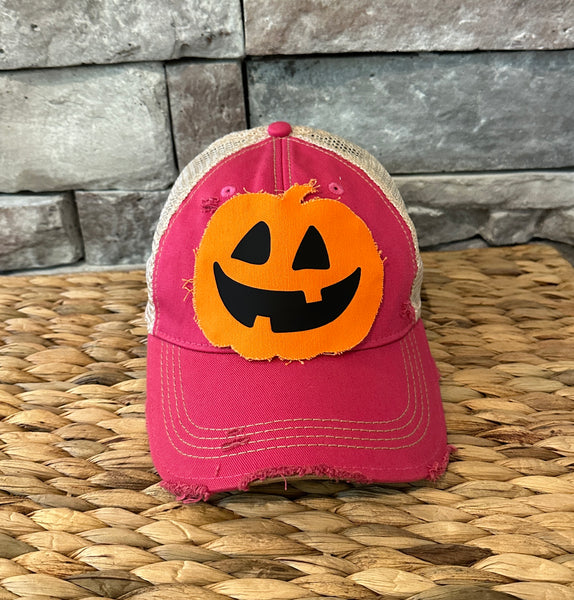 Jack-o’-Lantern hat by BohoGroove with orange pumpkin face design on a pink vintage distressed snapback trucker hat.