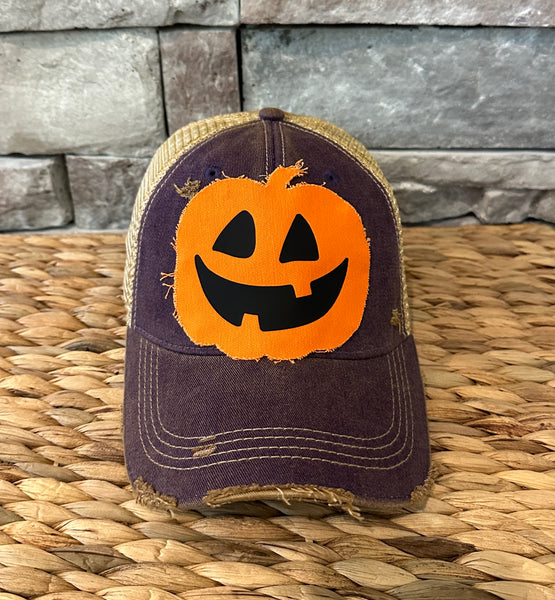 Jack-o’-Lantern hat by BohoGroove with orange pumpkin face design on a purple vintage distressed snapback trucker hat.