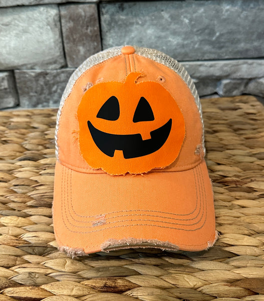 Jack-o’-Lantern hat by BohoGroove with orange pumpkin face design on a sherbet vintage distressed snapback trucker hat.