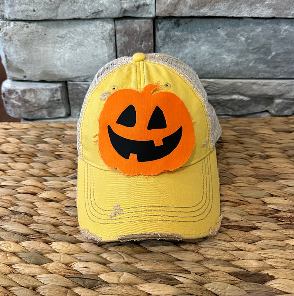 Jack-o’-Lantern hat by BohoGroove with orange pumpkin face design on a yellow vintage distressed snapback trucker hat.