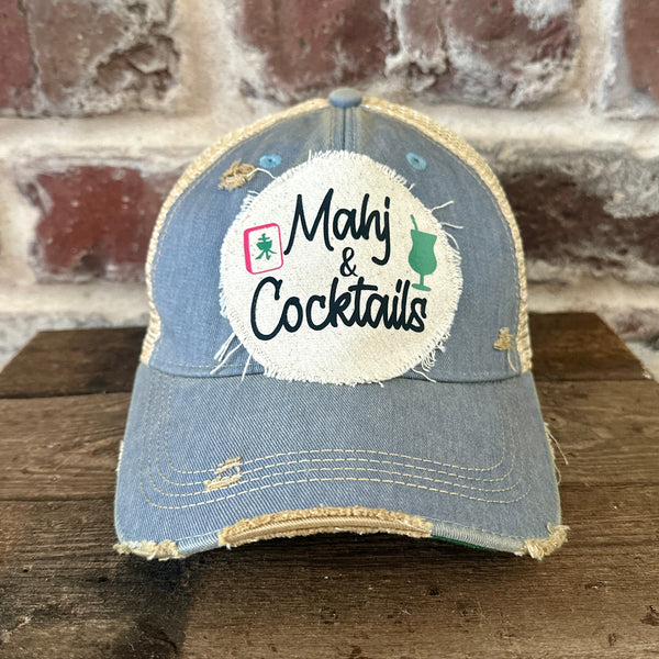 Mahj & Cocktails hat by BohoGroove featuring black Mahj & Cocktails lettering with a green cocktail graphic and Mahjong tile graphic on an off-white distressed patch on a light blue vintage distressed snapback trucker hat.
