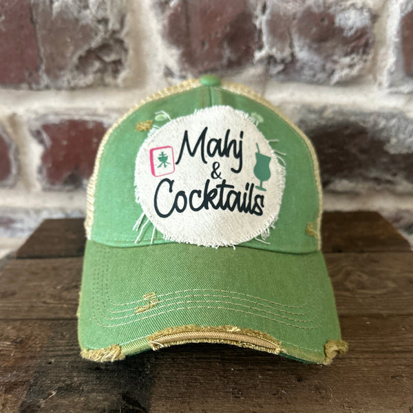 Mahj & Cocktails hat by BohoGroove featuring black Mahj & Cocktails lettering with a green cocktail graphic and Mahjong tile graphic on an off-white distressed patch on a mint vintage distressed snapback trucker hat.