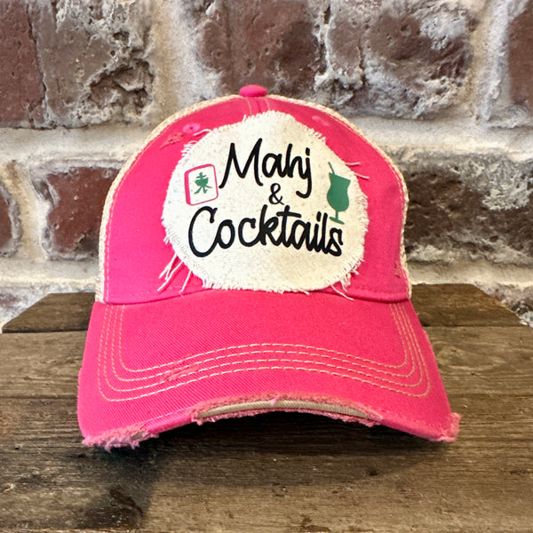 Mahj & Cocktails hat by BohoGroove featuring black Mahj & Cocktails lettering with a green cocktail graphic and Mahjong tile graphic on an off-white distressed patch on a pink vintage distressed snapback trucker hat.