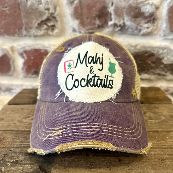 Mahj & Cocktails hat by BohoGroove featuring black Mahj & Cocktails lettering with a green cocktail graphic and Mahjong tile graphic on an off-white distressed patch on a purple vintage distressed snapback trucker hat.