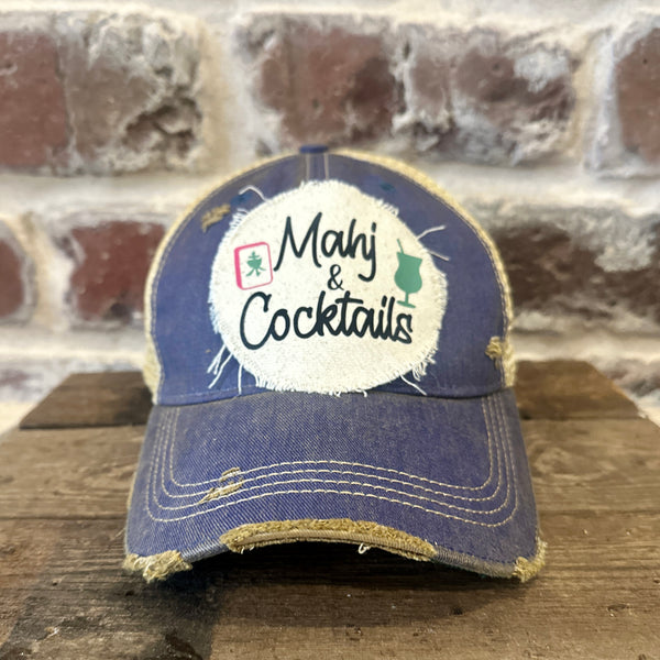 Mahj & Cocktails hat by BohoGroove featuring black Mahj & Cocktails lettering with a green cocktail graphic and Mahjong tile graphic on an off-white distressed patch on a royal vintage distressed snapback trucker hat.