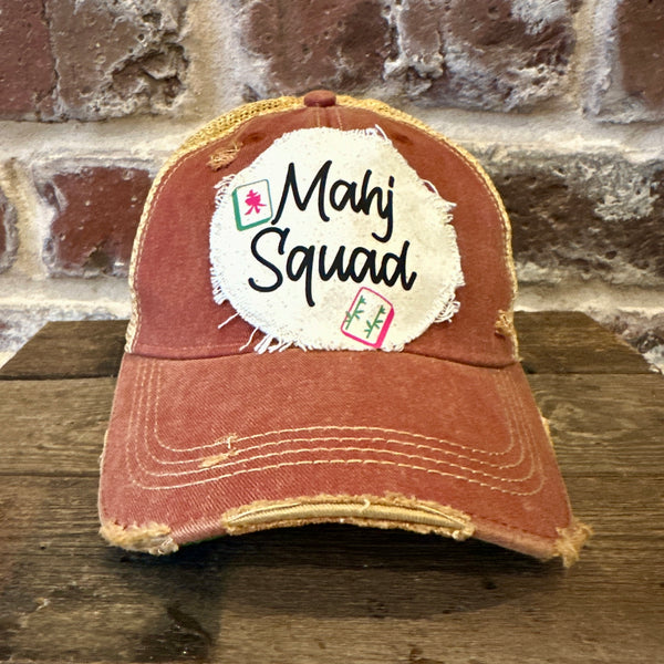 Mahj Squad hat by BohoGroove featuring black Mahj Squad lettering with Mahjong tile graphics on an off-white distressed patch on a brick red vintage distressed snapback trucker hat.