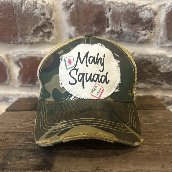Mahj Squad hat by BohoGroove featuring black Mahj Squad lettering with Mahjong tile graphics on an off-white distressed patch on a camo vintage distressed snapback trucker hat.